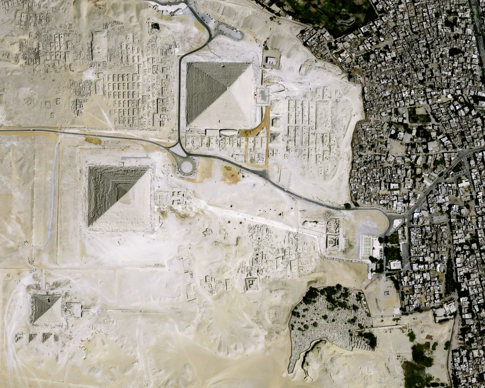 Satellite photograph of the three Giza pyramids, plateau roads and the boundary between desert and dense urban neighbourhoods